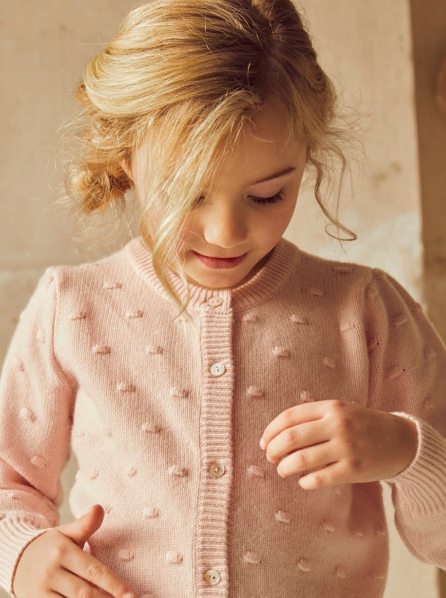 This stylish 4 ply cardigan comes with gentle puff sleeves, a long bottom rib to accentuate the waist, and lots and lots of Bobbles. After all, who doesn’t LOVE Bobbles? A fun addition to any winter wardrobe, it is made with the softest cashmere/merino blend from Inner Mongolia, and will keep your Little One stylish and warm all winter long.