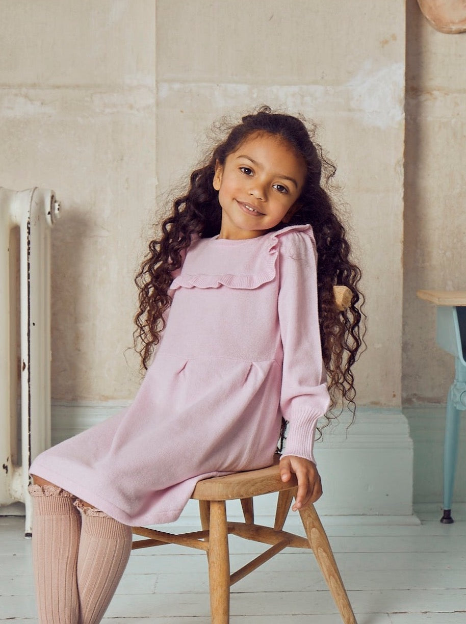 This lovely dress has gentle puff sleeves and a stylish ruffle down and across the chest. It also comes with pleats at the waistline for added femininity and is bright pink to chase away those winter blues. Made with the softest cashmere/ merino blend from Inner Mongolia, it will keep your Little One stylish and warm all winter long.