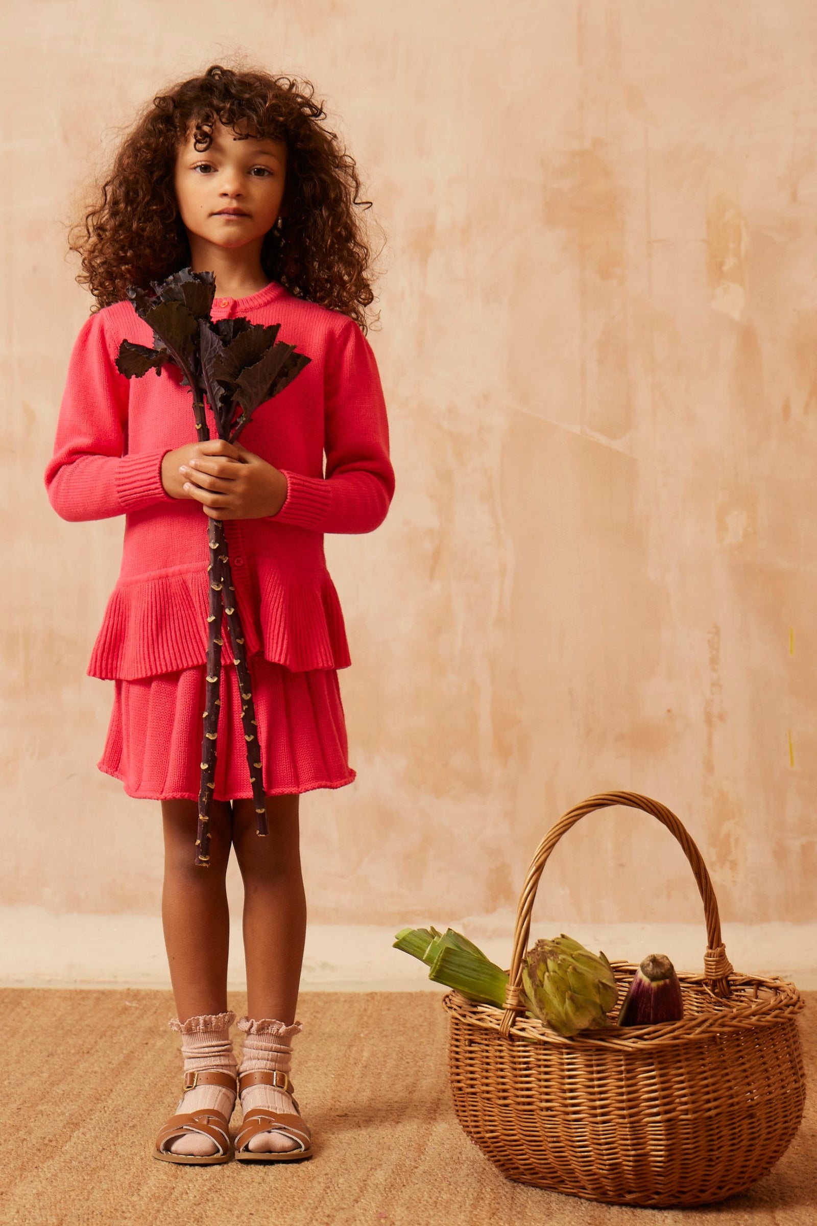 Young girl in the raspberry Ruffled Hem Jacket from MIKA & MILO, organic cotton and cashmere knit with ruffle hem