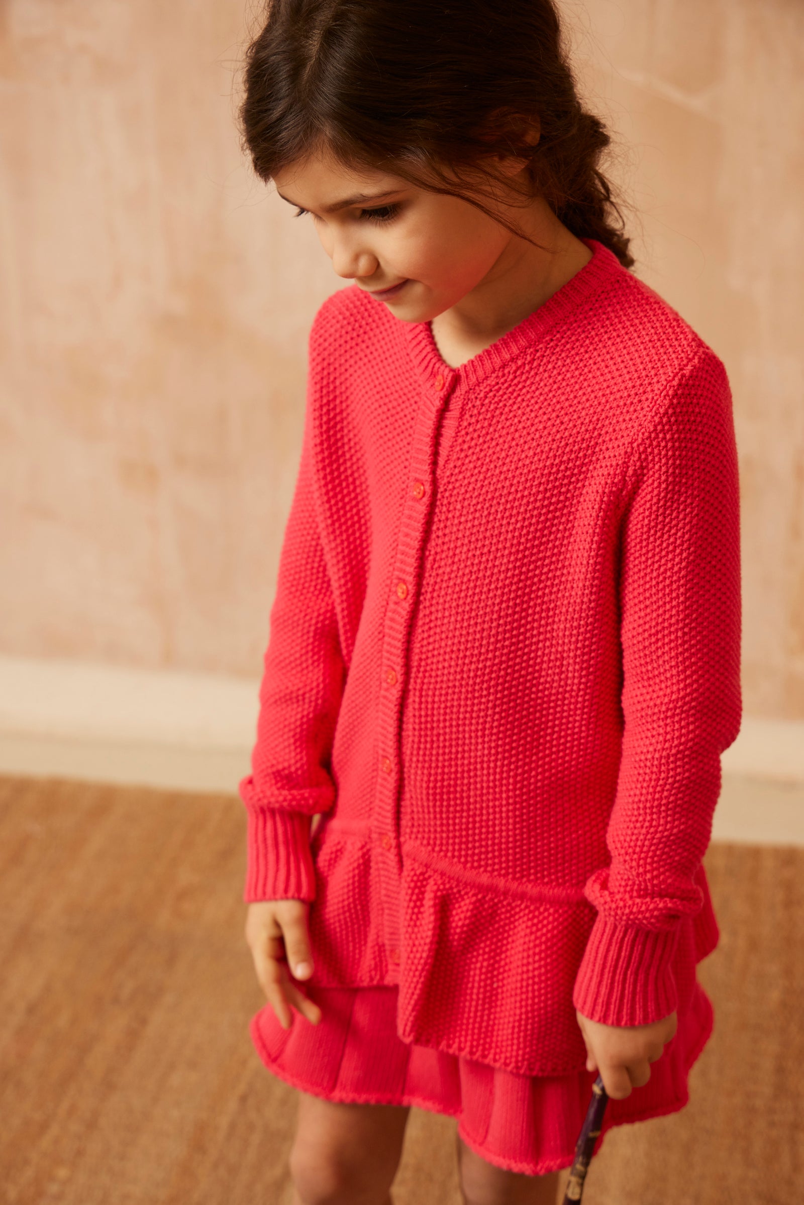Young girl in the raspberry Moss Stitch Ruffled Cardigan from MIKA & MILO, organic cotton and cashmere knit