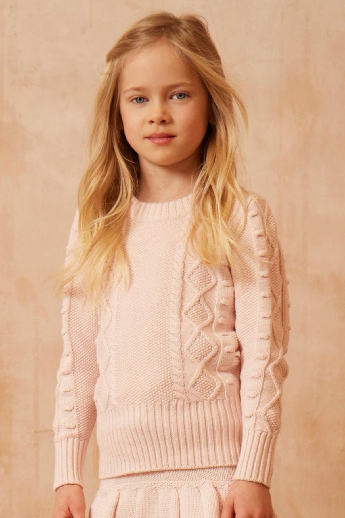 Young girl in a blush Cable Popcorn Jumper from MIKA & MILO, dense organic cotton and cashmere knit