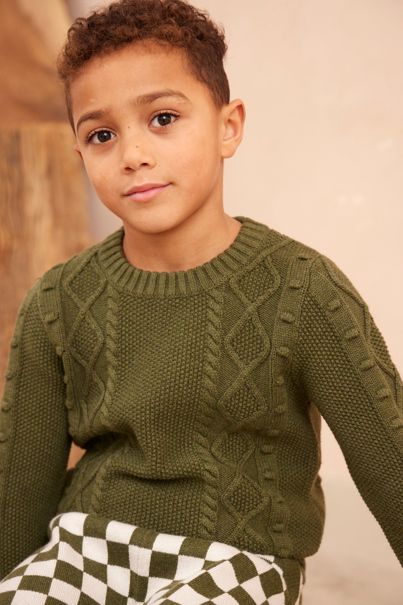 Boy wearing the MIKA & MILO Cable Popcorn Jumper in deep avocado green
