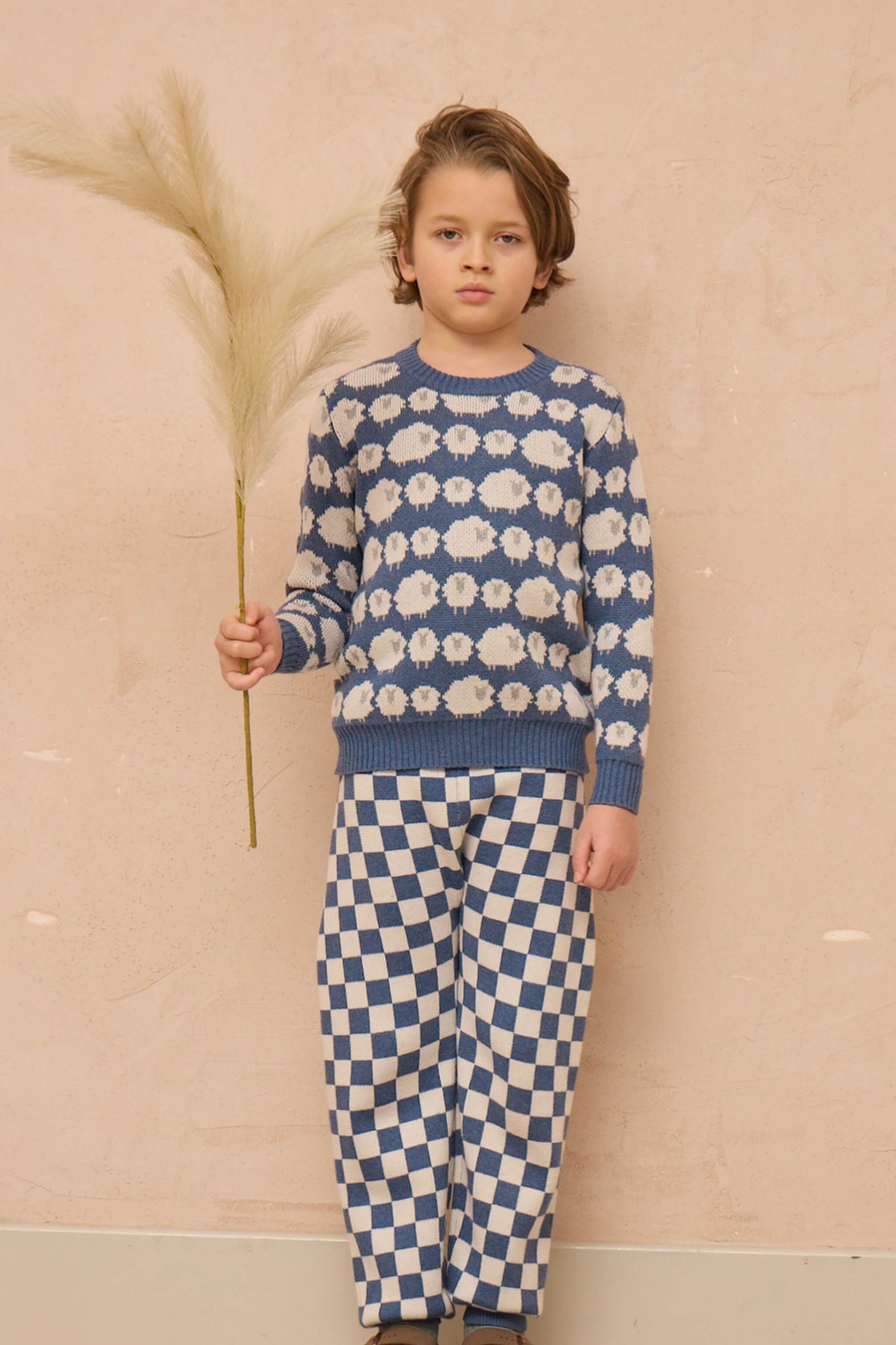 Side view of a boy in the Flock of Sheep Jumper in bluestone blue