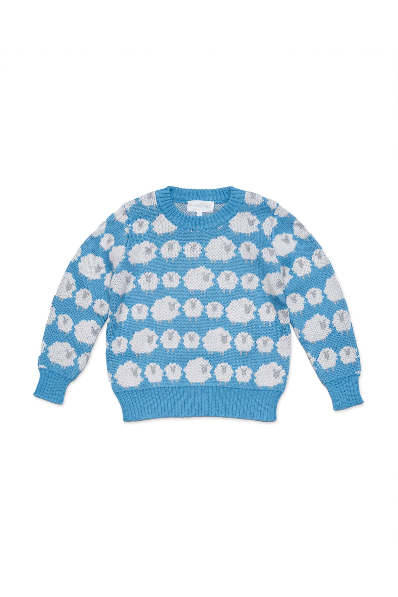 Boy standing against a plaster wall in the Flock of Sheep Jumper in Iceland blue