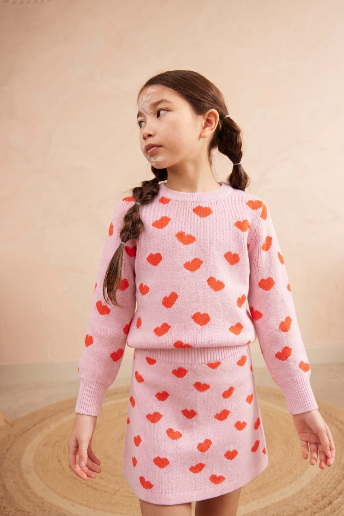Girl wearing the Love Hearts jumper and skirt set in bubble gum pink