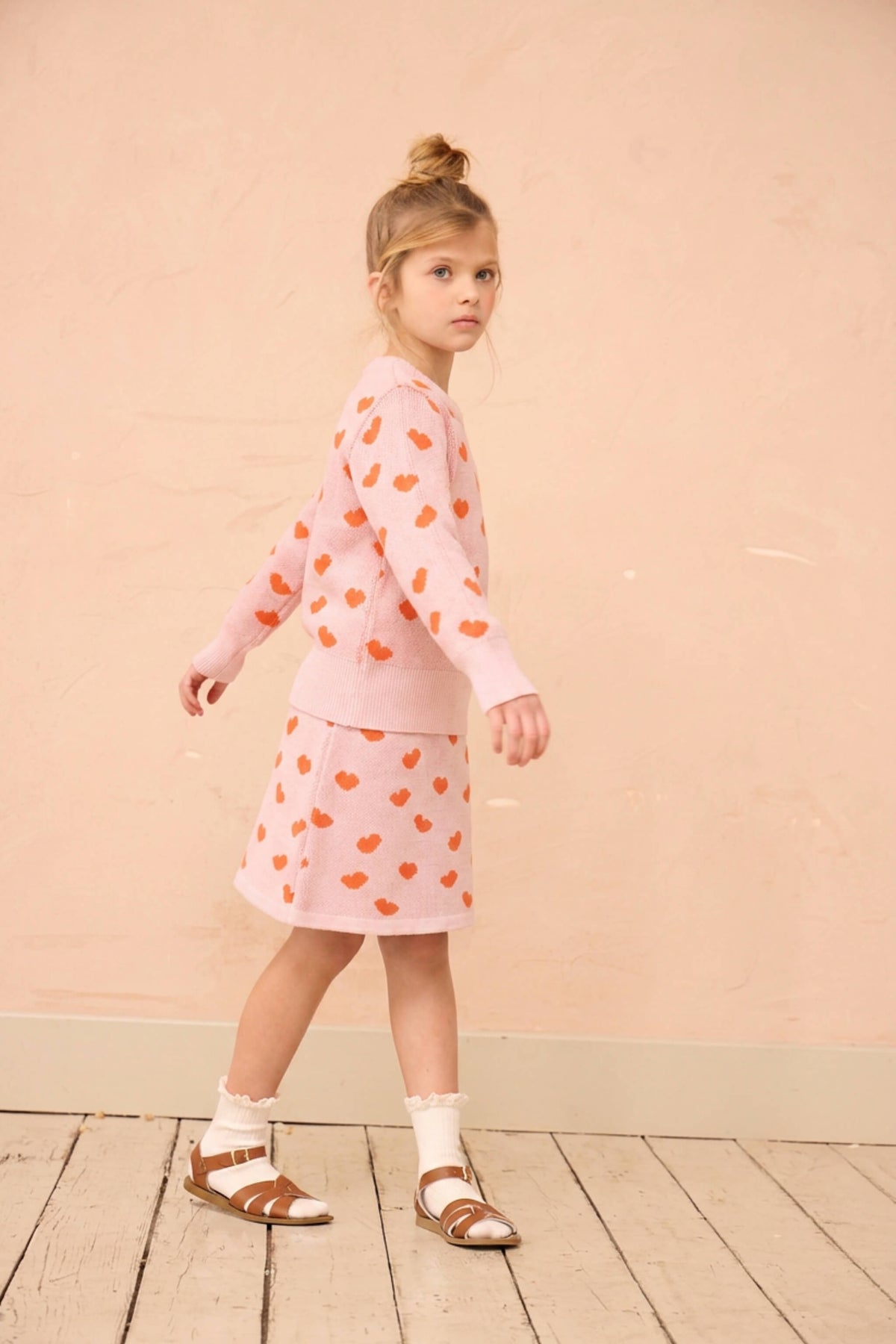 Girl wearing the Love Hearts skirt and jumper set in rose pink
