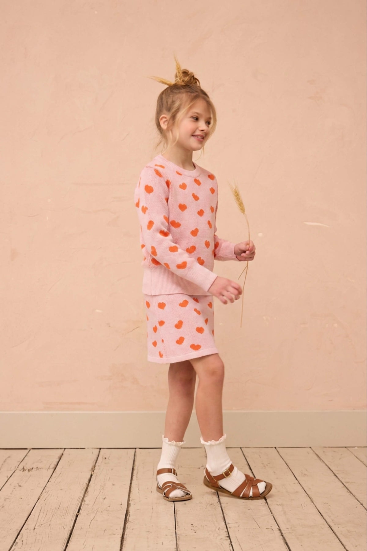 Girl standing against a plaster wall in the Love Hearts set in rose pink