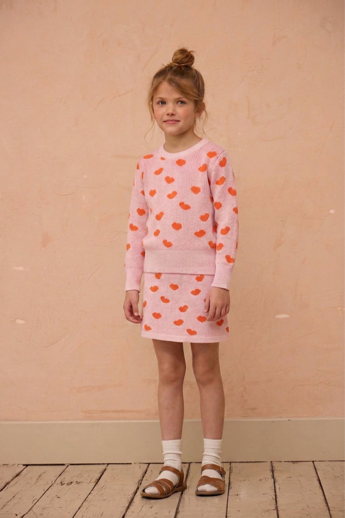 Side view of a girl in the Love Hearts jumper and skirt in rose pink