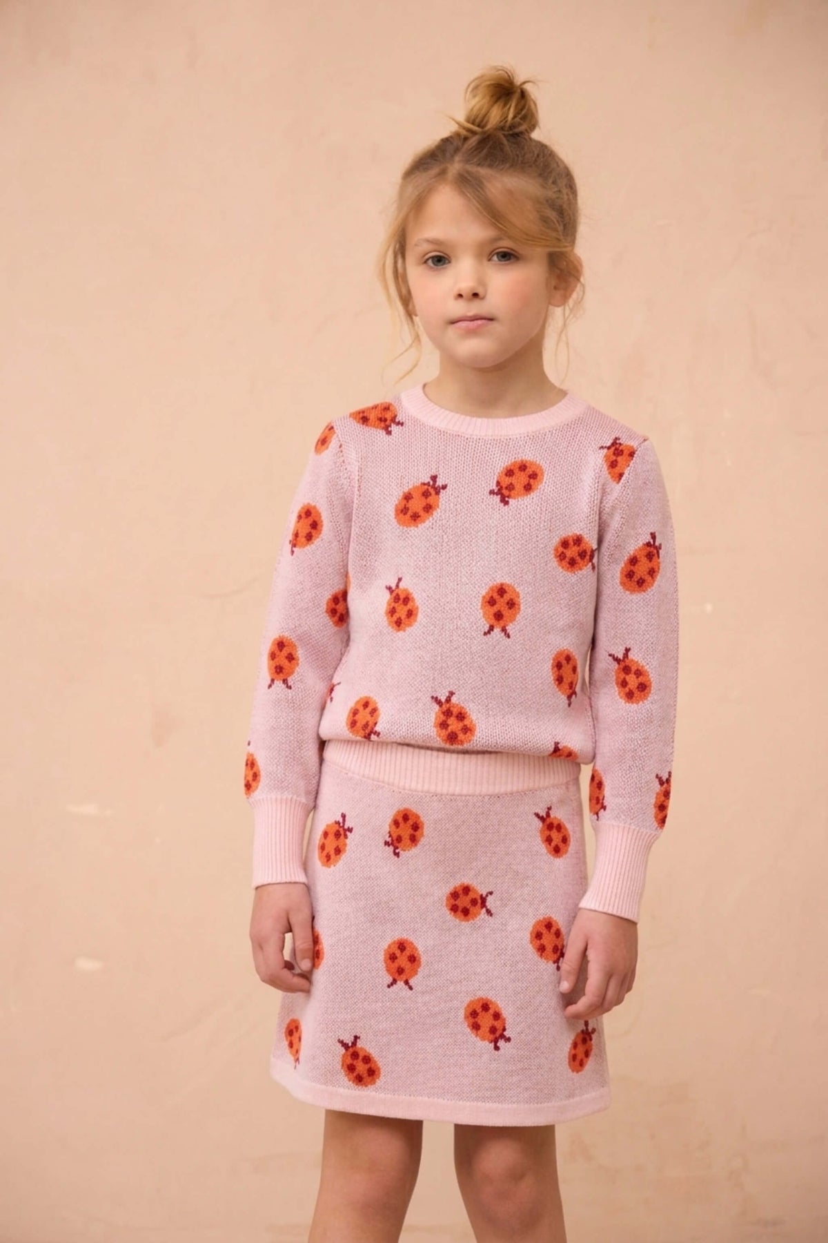 Girl wearing the MIKA & MILO Ladybird jumper and skirt set in rose pink