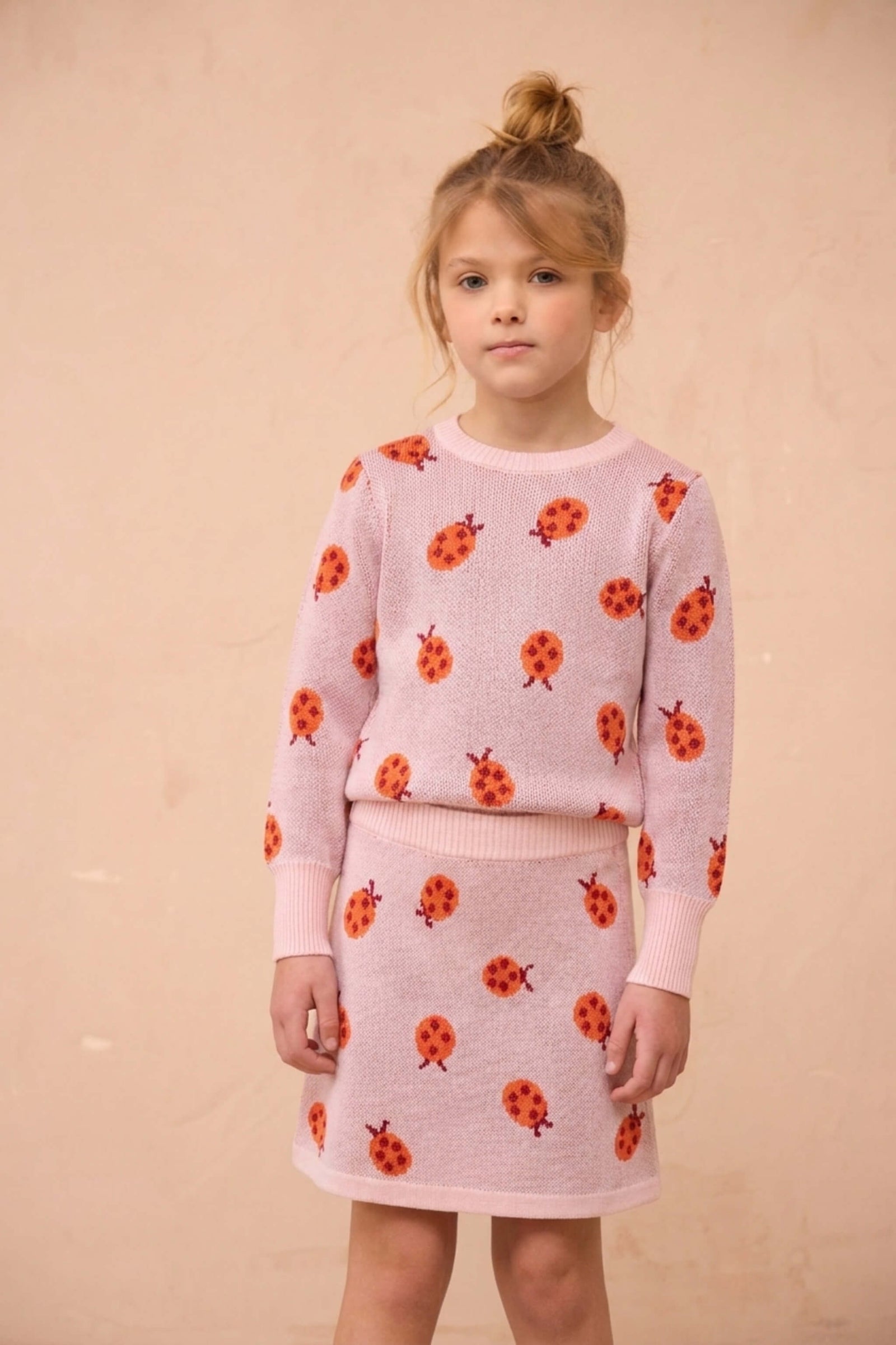 Girl wearing the MIKA & MILO Ladybird jumper and skirt set in rose pink