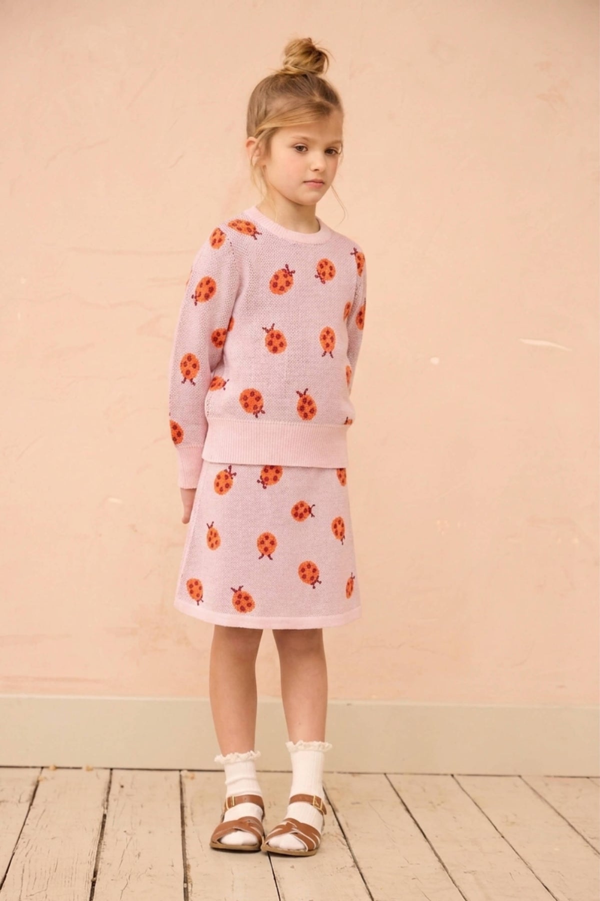 Side view of a girl in the Ladybird jumper and skirt in rose pink