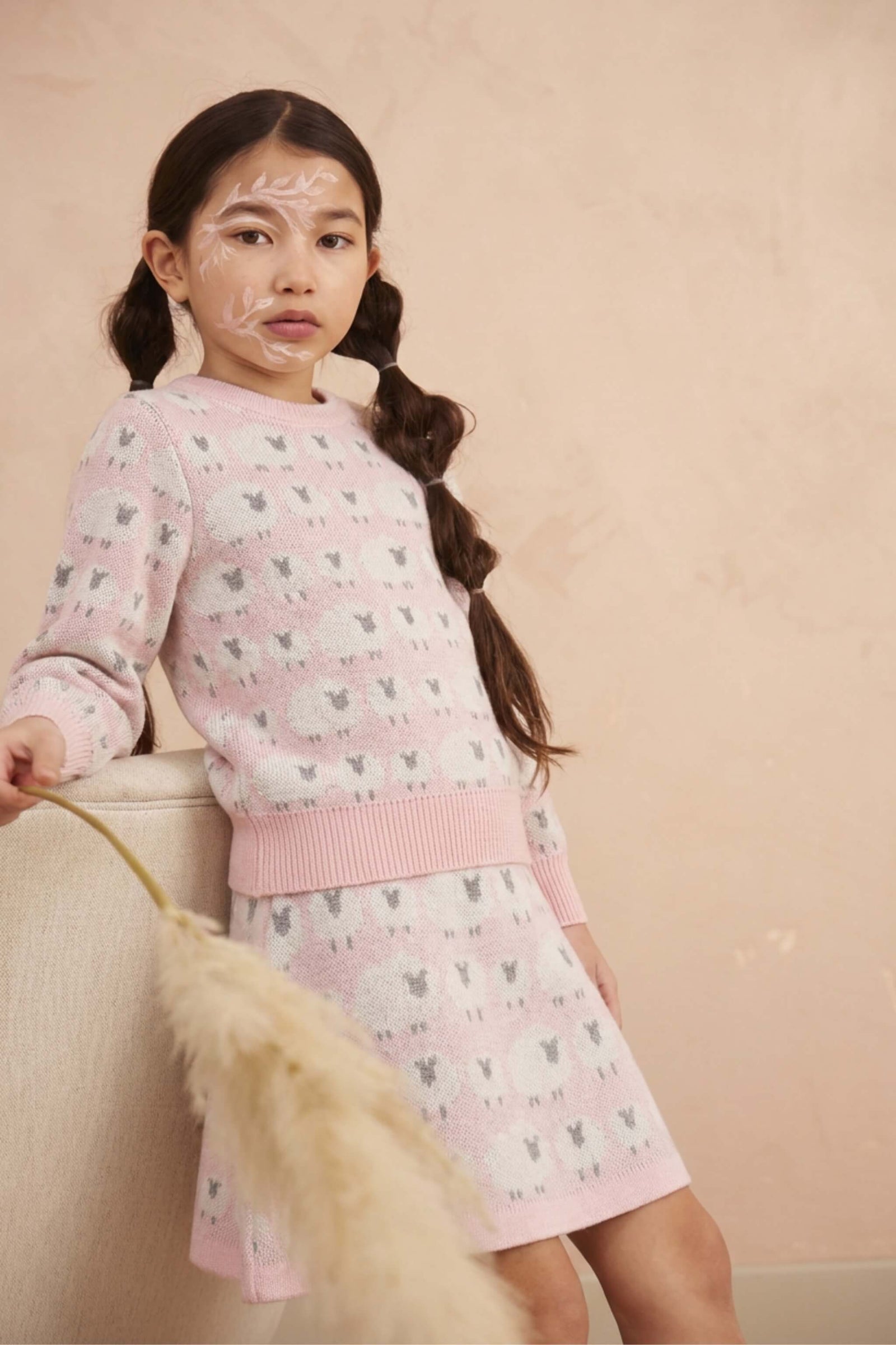 Girl standing against a plaster wall in the Little Bo Peep set in rose pink