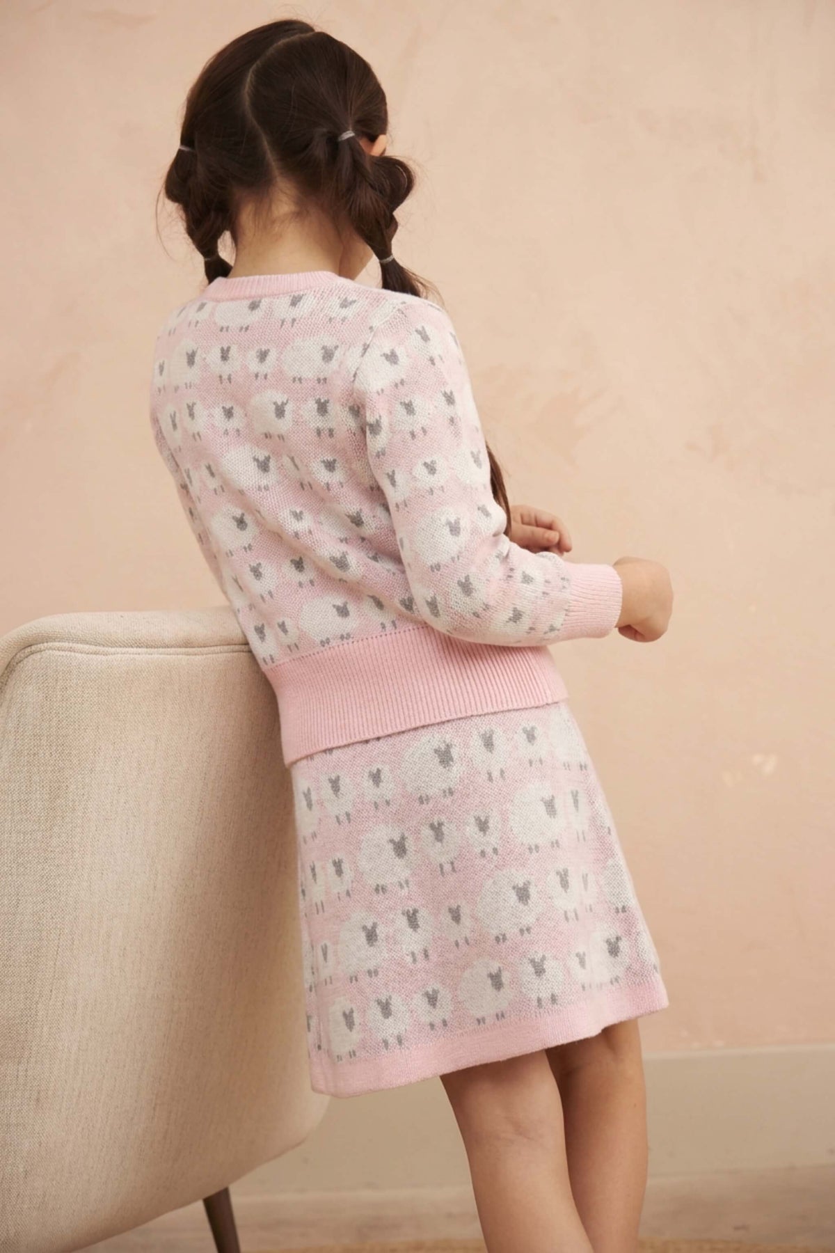 Side view of a girl in the Little Bo Peep jumper and skirt in rose pink