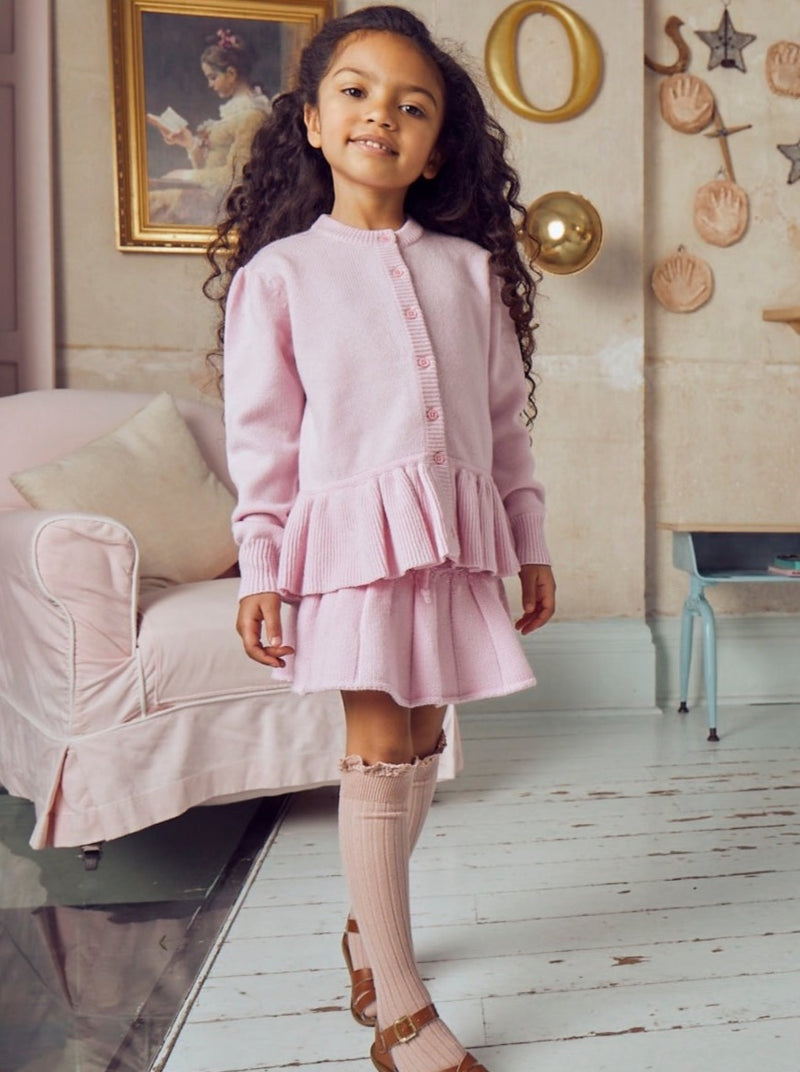 This timeless 4 ply Jacket comes with a lovely ruffle at the bottom for simple elevated feminity. Made with the softest cashmere/ merino blend from Inner Mongolia, it will keep your Little One cosy and warm all winter long.   Team it up with our matching pleated Tennis Skirt in Blossom for a head-to-toe cosy feel. 